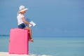 Little tourists girl with big suitcase on tropical white beach Royalty Free Stock Photo