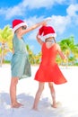 Little adorable girls in Santa hats during beach vacation have fun together Royalty Free Stock Photo