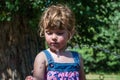 A little adorable little girl, a baby in a dress, drinks water from a spout of a Roman drinking fountain on a hot summer day, quen Royalty Free Stock Photo