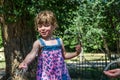 A little adorable little girl, a baby in a dress, drinks water from a spout of a Roman drinking fountain on a hot summer day, quen Royalty Free Stock Photo