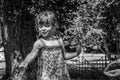 A little adorable little girl, a baby in a dress, drinks water from a spout of a Roman drinking fountain on a hot summer day, quen Royalty Free Stock Photo