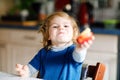 Little adorable toddler girl eating big red apple. Vitamin and healthy food for small children. Portrait of beautiful