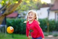 Little adorable toddler girl playing with ball outdoors. Happy smiling child catching and throwing, laughing and making