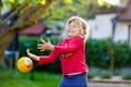 Little adorable toddler girl playing with ball outdoors. Happy smiling child catching and throwing, laughing and making