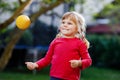 Little adorable toddler girl playing with ball outdoors. Happy smiling child catching and throwing, laughing and making Royalty Free Stock Photo