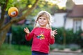 Little adorable toddler girl playing with ball outdoors. Happy smiling child catching and throwing, laughing and making Royalty Free Stock Photo