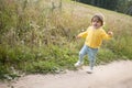 Little adorable toddler walking on country road in the summer field. children vacation on countryside