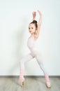 A little adorable young ballerina does ballet poses and stretching exercises on the floor at home Royalty Free Stock Photo