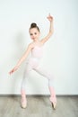 A little adorable young ballerina does ballet poses and stretching exercises on the floor at home Royalty Free Stock Photo