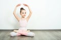 A little adorable young ballerina does ballet poses and stretching exercises on the floor at home Royalty Free Stock Photo