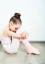 A little adorable young ballerina does ballet poses and stretching exercises on the floor at home Royalty Free Stock Photo