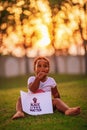 Little African-American baby girl sits on the green grass and holds the poster Black Lives Matter Royalty Free Stock Photo