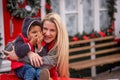 Little African American boy with Caucasian mother sits on the hood of Christmas vintage car Royalty Free Stock Photo