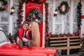 Little African American boy with Caucasian mother sits on the hood of Christmas vintage car Royalty Free Stock Photo