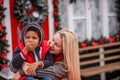 Little African American boy with Caucasian mother sits on the hood of Christmas vintage car Royalty Free Stock Photo