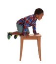 Little African-American boy climbing up  on white background. Danger at home Royalty Free Stock Photo