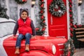 Little african american boy sitting on the hood of Christmas vintage car. Child fooling around Royalty Free Stock Photo