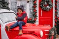 Little african american boy sitting on the hood of Christmas vintage car. Child fooling around Royalty Free Stock Photo