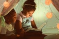 Little African-American children reading bedtime story in hovel Royalty Free Stock Photo