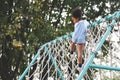 Little African American curly hair girl playing on park playground in spring or summer season. They enjoy climbing on the rope equ