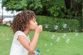 Little African American girl blowing bubbles in field Royalty Free Stock Photo