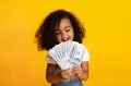 Little african-american girl holding money, yellow background