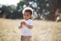 Little african boy standing on field with cupcake in hands Royalty Free Stock Photo