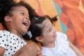 Little African and Caucasian kids girls smiling laughing and lying together on colorful mat on green grass Royalty Free Stock Photo