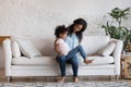 African daughter sits on mommy laps play together at home