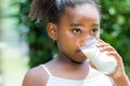 Little african girl drinking milk outdoors. Royalty Free Stock Photo