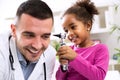 Little african girl holding otoscope and playing with pediatrician