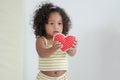 Little African girl holding a red small heart shape pillow with innocence face at home Royalty Free Stock Photo