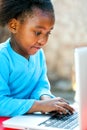 Little african girl typing on laptop. Royalty Free Stock Photo