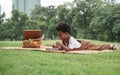 Little African kid boy crying and holding a sore finger when playing xylophone toys alone with sad face at park and lying down Royalty Free Stock Photo