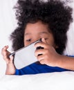 Little African kid playing with smartphone on bed Royalty Free Stock Photo