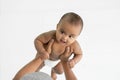 Little African newborn girl wear diaper smiling and enjoy with senior father lifting her up in the air.