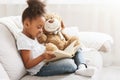 Little afro girl holding teddy bear and reading book Royalty Free Stock Photo