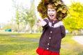 Little amusing girl in a wreath from autumn leaves