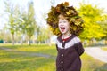 Little amusing girl in a wreath from autumn leaves