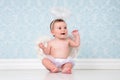 Little angel smiling and sitting on the floor. Royalty Free Stock Photo