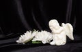 Little angel with wings on a black background and flowers, free space for text. Concept of memory of a person, funeral Royalty Free Stock Photo