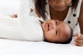 A little Asian African newborn infant baby girl lying on white bed with her sister who hugging and kissing her, sweet adorable kid Royalty Free Stock Photo