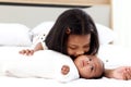 A little Asian African newborn infant baby girl lying on white bed with her sister who hugging and kissing her, sweet adorable kid Royalty Free Stock Photo