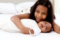 A little Asian African newborn infant baby girl lying on white bed with her sister who hugging and kissing her, sweet adorable kid Royalty Free Stock Photo