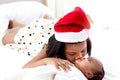 Little Asian African newborn infant baby girl lying on white bed with sister wearing red Christmas Santa hat while hugging and Royalty Free Stock Photo