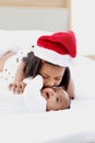 Little Asian African newborn infant baby girl lying on white bed with sister wearing red Christmas Santa hat while hugging and Royalty Free Stock Photo