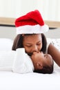 Little Asian African newborn infant baby girl lying on white bed with sister wearing red Christmas Santa hat while hugging and Royalty Free Stock Photo