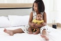 Little Asian African newborn infant baby girl sitting on white bed with her sister who hugging and playing with her, sweet Royalty Free Stock Photo