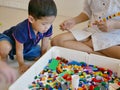 Little Asian baby being interested looking at colorful interlocking plastic bricks toy