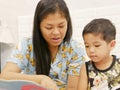 Little Asian baby enjoy listening to her mother reading a book aloud to her